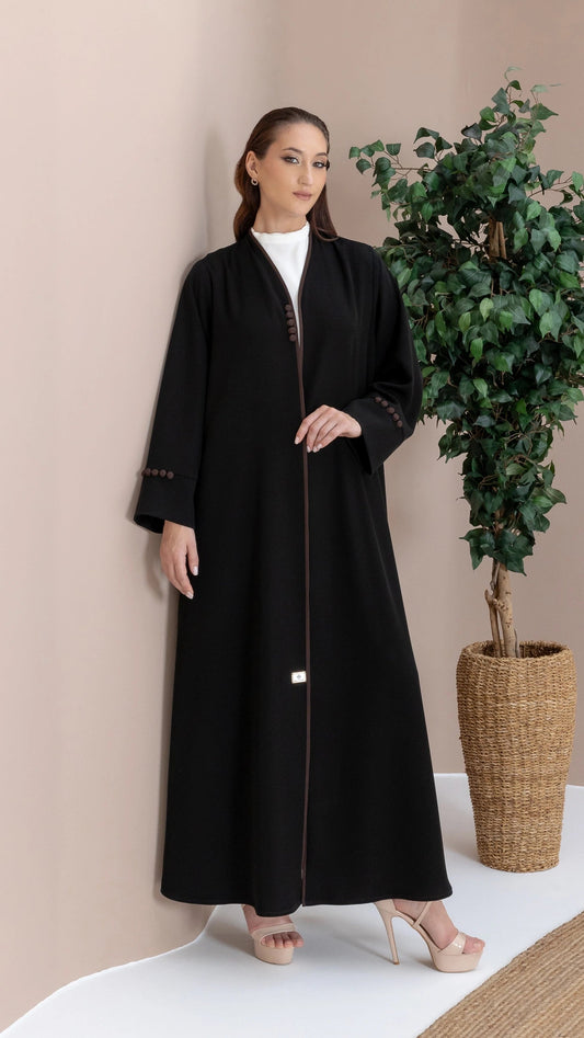 Leen Noir Abaya deatures a Mocha Trim piping that contrasts with the classic black elegantly with tone to tone button accents