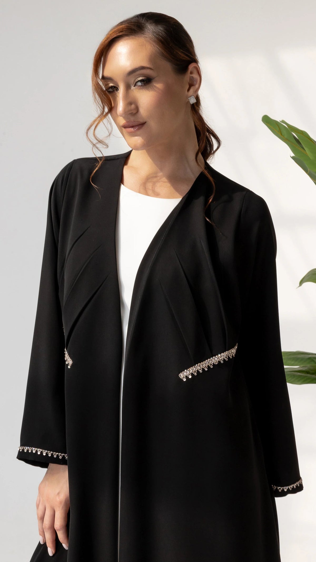 DOUNIA Noir Lumiere Close-up portrait of DOUNIA Noir Lumière abaya showcasing refined crystal trim detailing