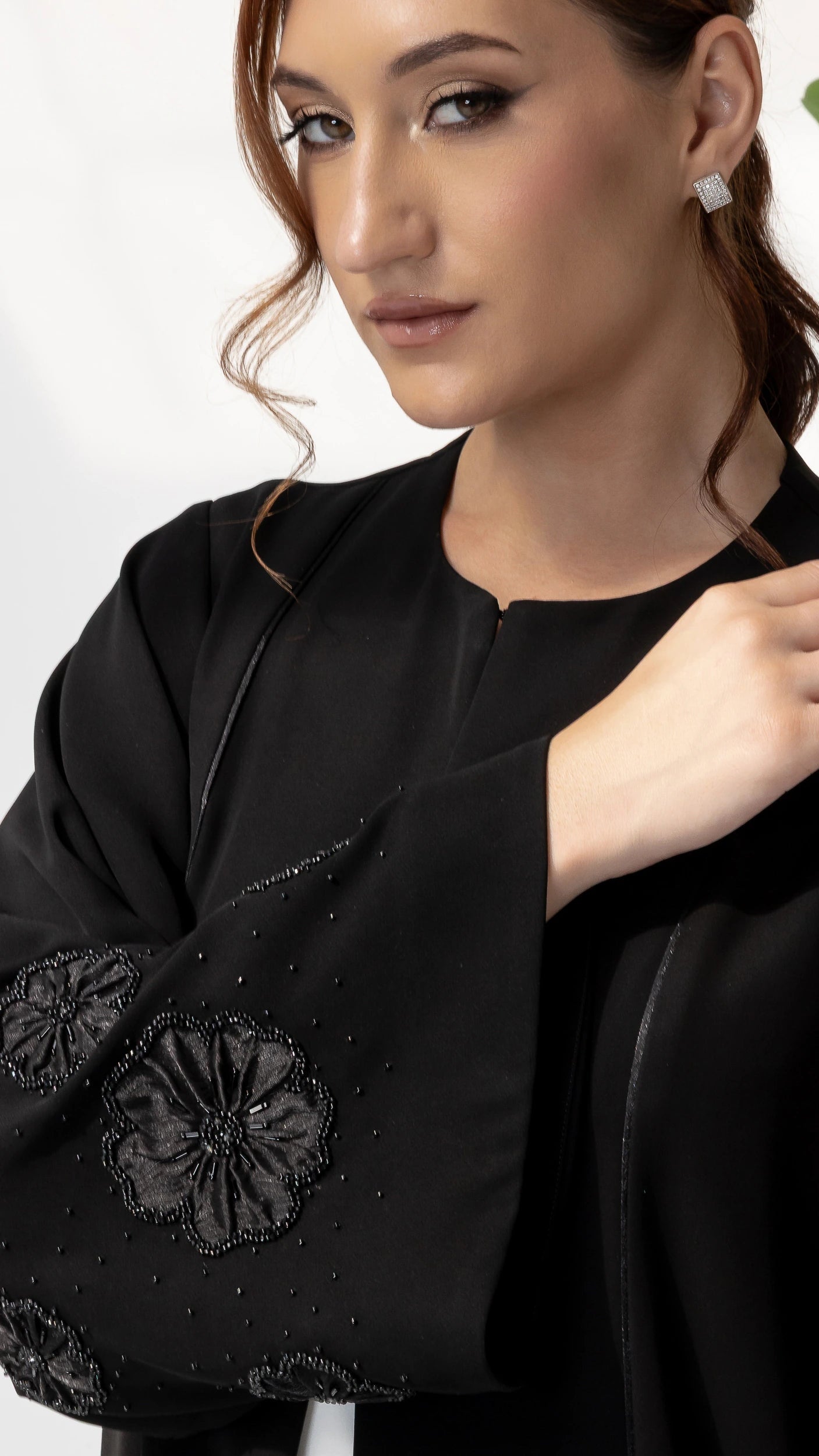 NAFISA | Noir Blossom Luxe Abaya, close-up portrait showcasing intricate black floral appliqué sleeve craftsmanship