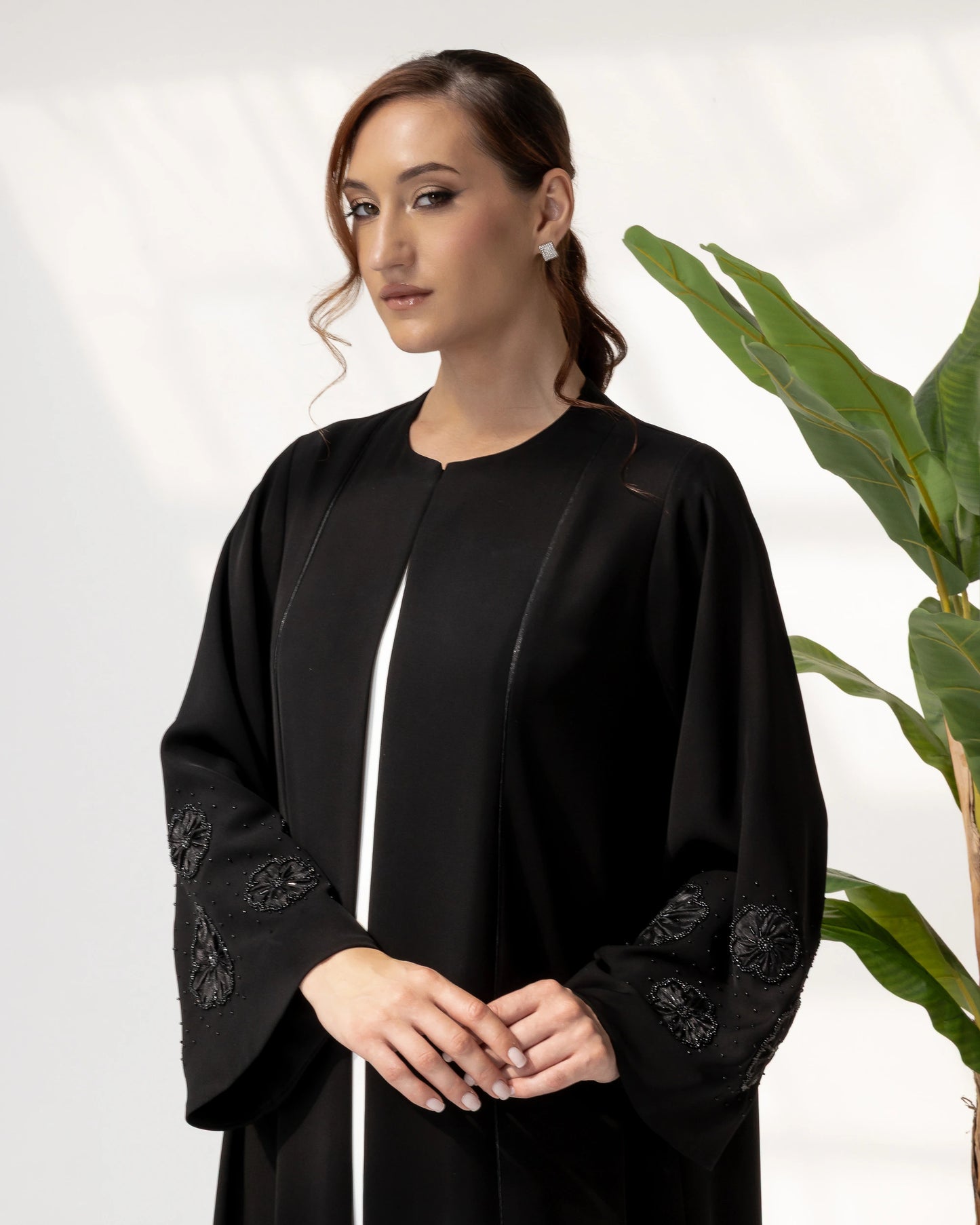 NAFISA | Noir Blossom Luxe Abaya close-up portrait showcasing intricate black floral appliqué sleeve craftsmanship