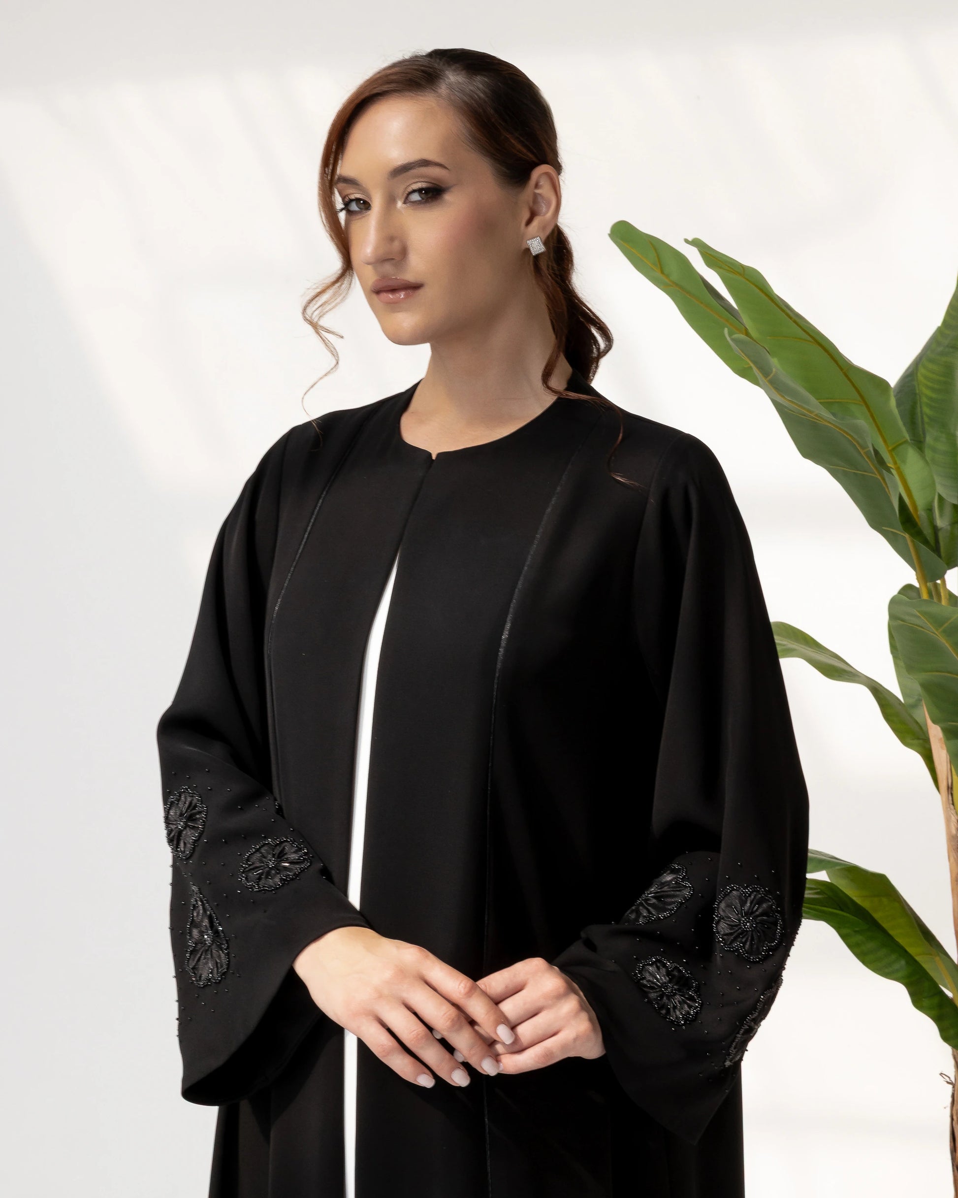 NAFISA | Noir Blossom Luxe Abaya close-up portrait showcasing intricate black floral appliqué sleeve craftsmanship